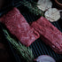 Raw bavette steak on a grill with herbs and garlic cloves.