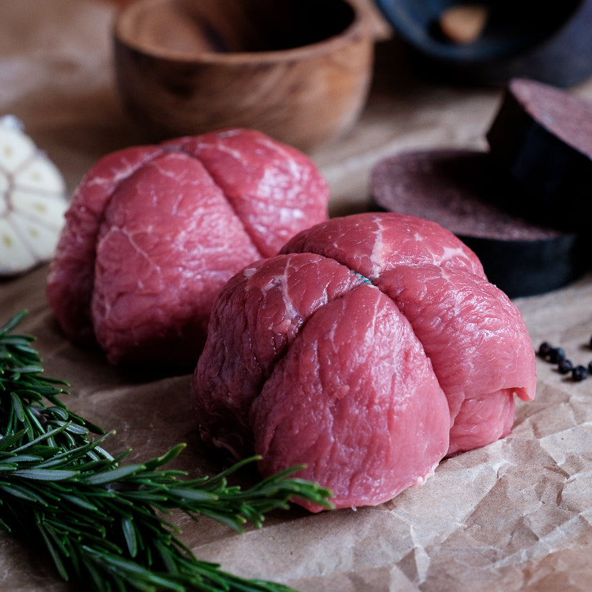 Raw beef olives on a wooden surface with black pudding herbs and spices