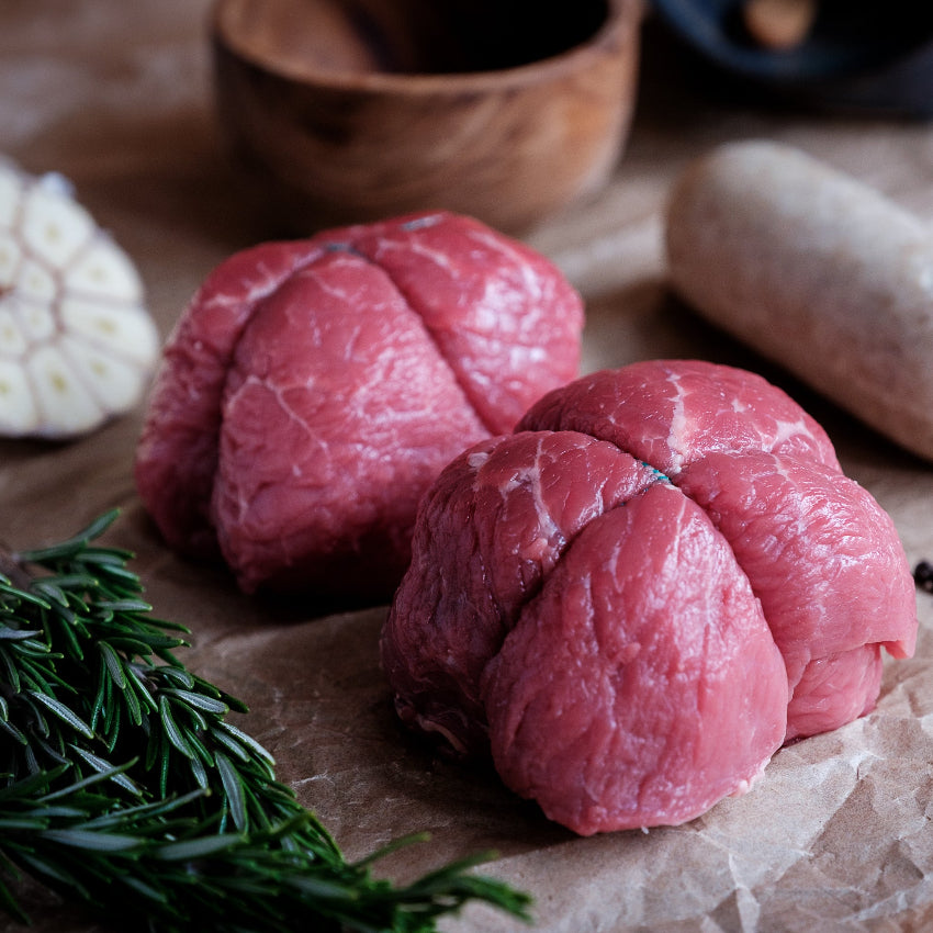 Raw beef olive with white pudding, garlic, rosemary, and peppercorns on brown paper
