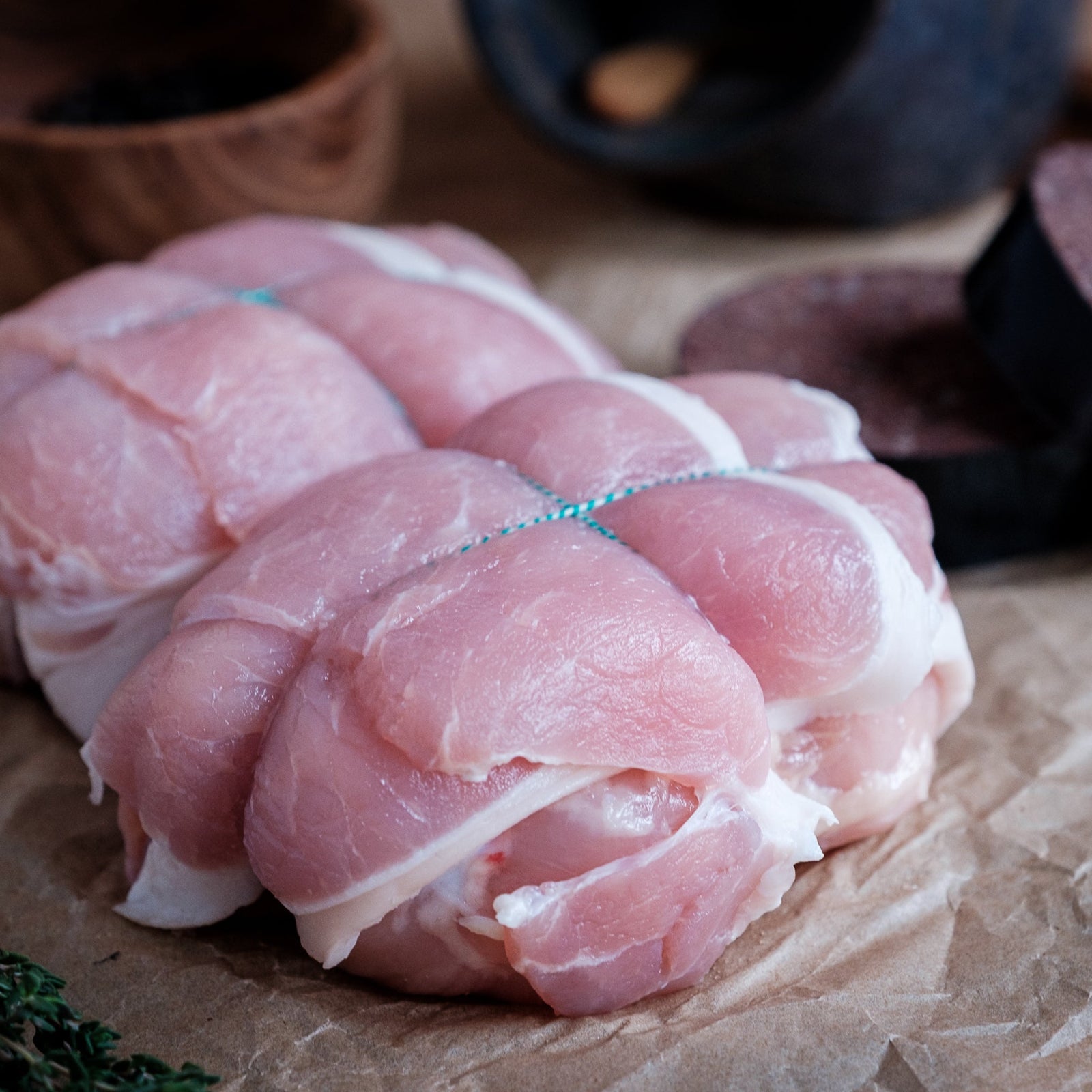 Raw chicken olive tied with string on a rustic wooden surface
