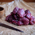 Diced Lamb on crumpled paper with a wooden bowl and knife.