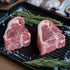 Two raw lamb chops on a grill pan with rosemary and salt.