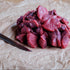Raw beef chunks on crumpled brown paper with a knife