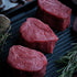Raw fillet steaks on a grill with rosemary and a wooden background