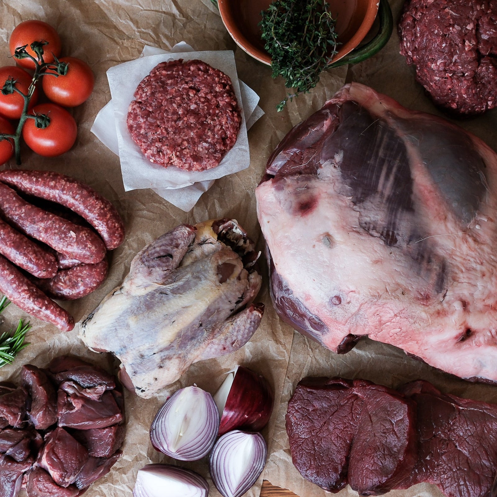 Assorted raw meats and ingredients on a wooden surface