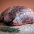 Raw ox heart on a wooden cutting board with herbs and salt