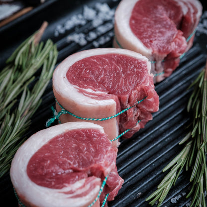Raw lamb noisette on a grill with rosemary and salt
