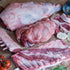 Raw meat cuts on a wooden cutting board with vegetables