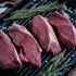 Raw lamb leg steaks on a grill with rosemary and salt