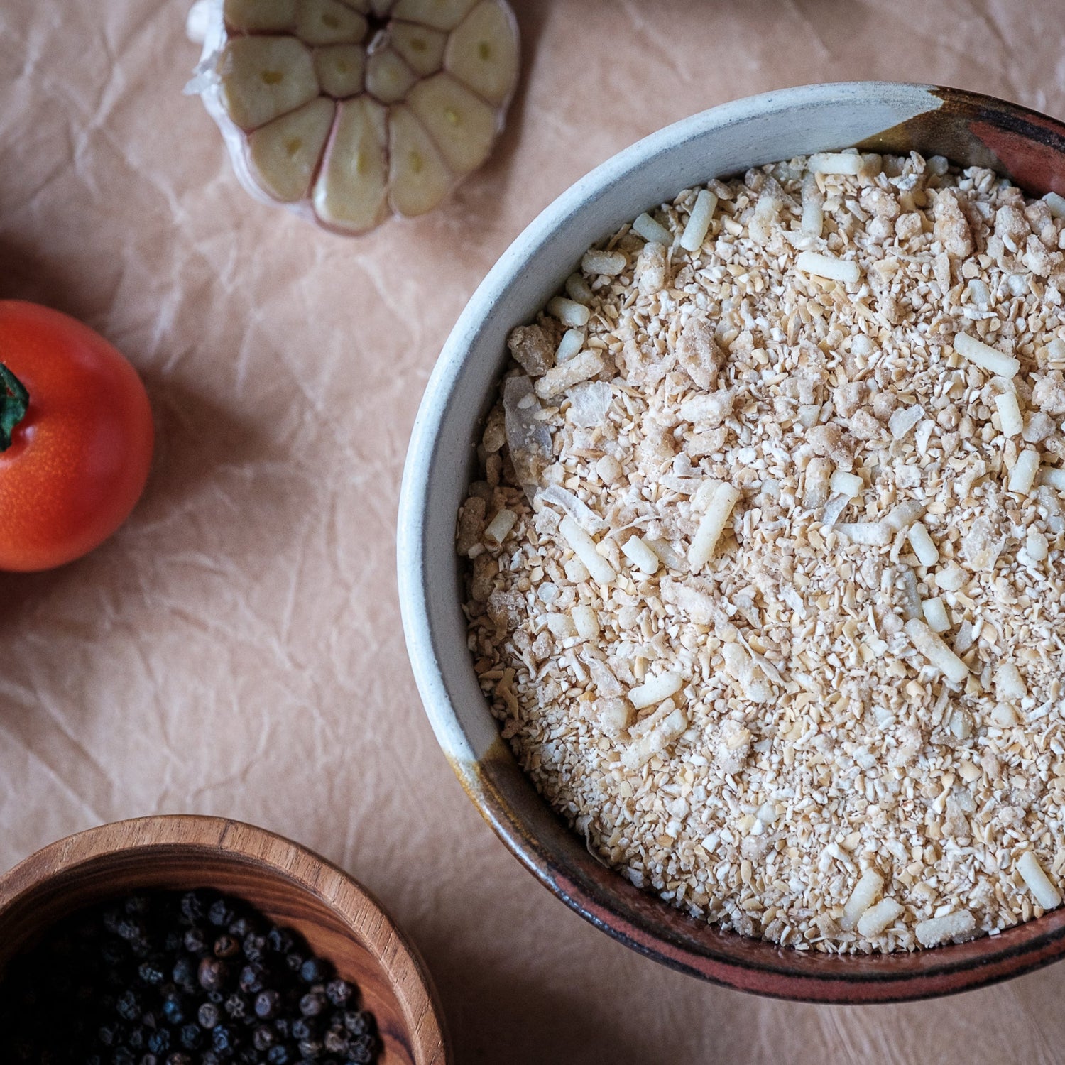 Bowl of oatmeal with tomatoes and a wooden spoon on brown paper