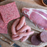 Raw meat products including sausages, ground meat, and cured meat on a wooden surface.