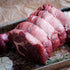 Raw rolled rib eye on a baking tray with onions and garlic