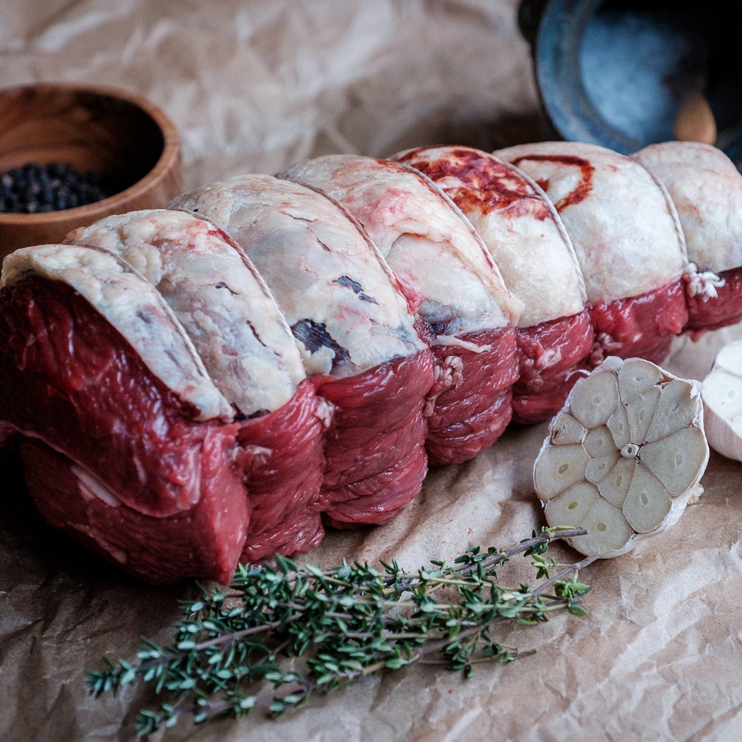 Raw rolled rump roast with herbs on a rustic surface