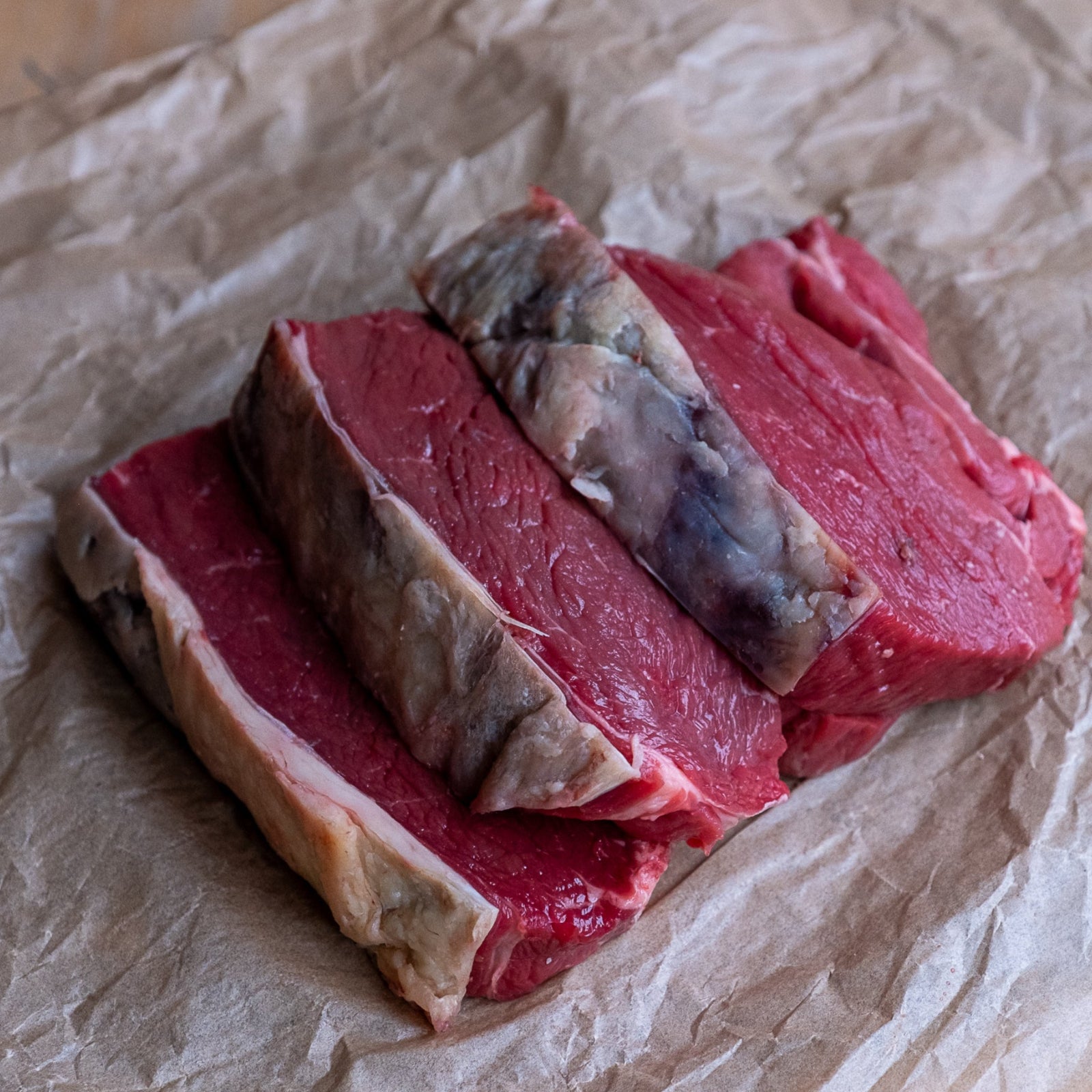 Raw rump steaks on crumpled brown paper
