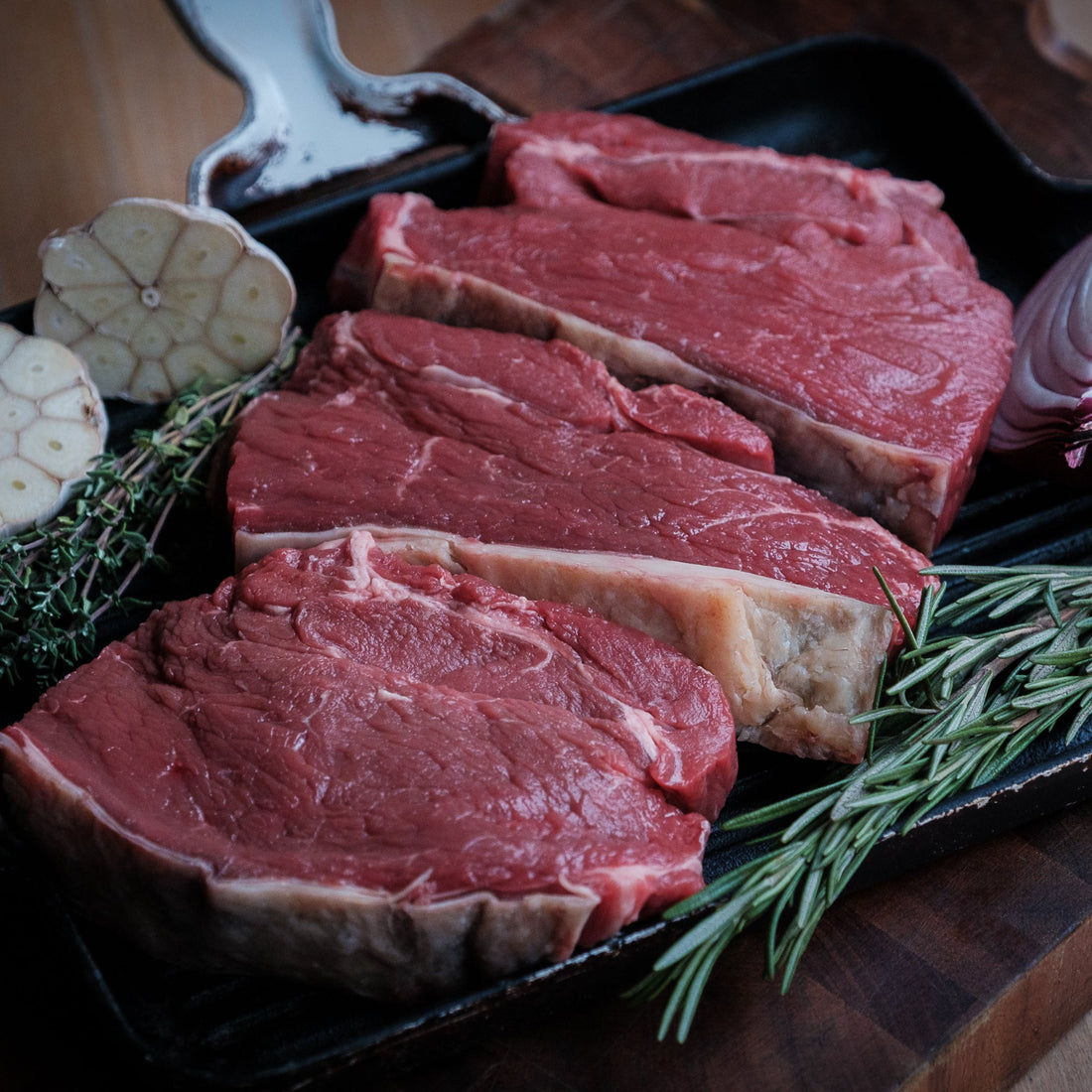 Rump Steak on a skillet with herbs, garlic &amp; onion