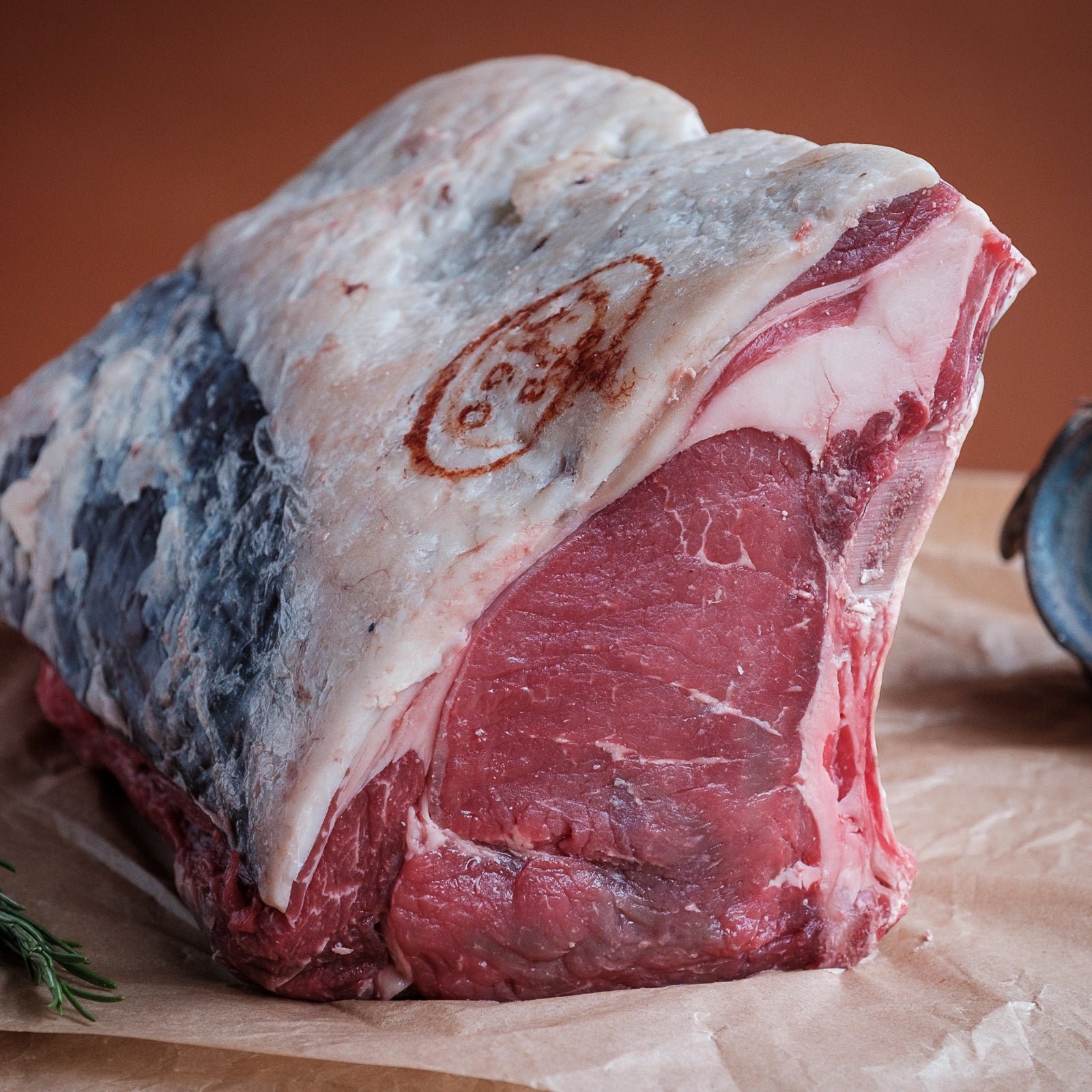 Raw beef sirloin on the bone on a wooden surface with a brown background