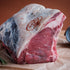 Raw beef sirloin on the bone on a wooden surface with a brown background