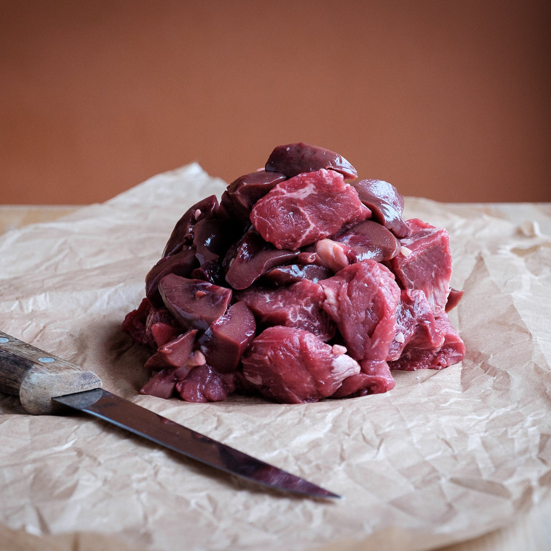 Raw steak &amp; kidney on a wooden surface with a knife