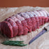 Raw beef topside dry aged for 50 days on crumpled paper with a knife and rosemary.
