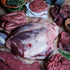 Assorted wild roe cuts including a large cut of beef, ground meat, and sausages on a wooden surface.